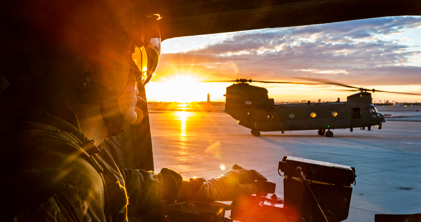 Soldiers on board a helicopter looks out to a Chinook helicopter on the runway