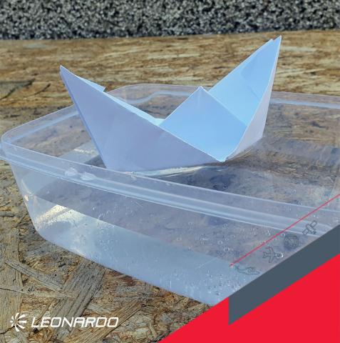 Paper boat floating on water in a plastic box