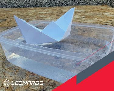 Paper boat floating on water in a plastic box