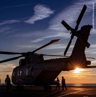 Silhouette of Merlin helicopter on deck of Royal Navy ship