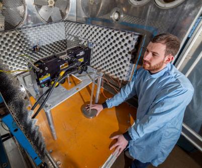 Young man in lab coat works with precision engineering equipment at our Edinburgh site