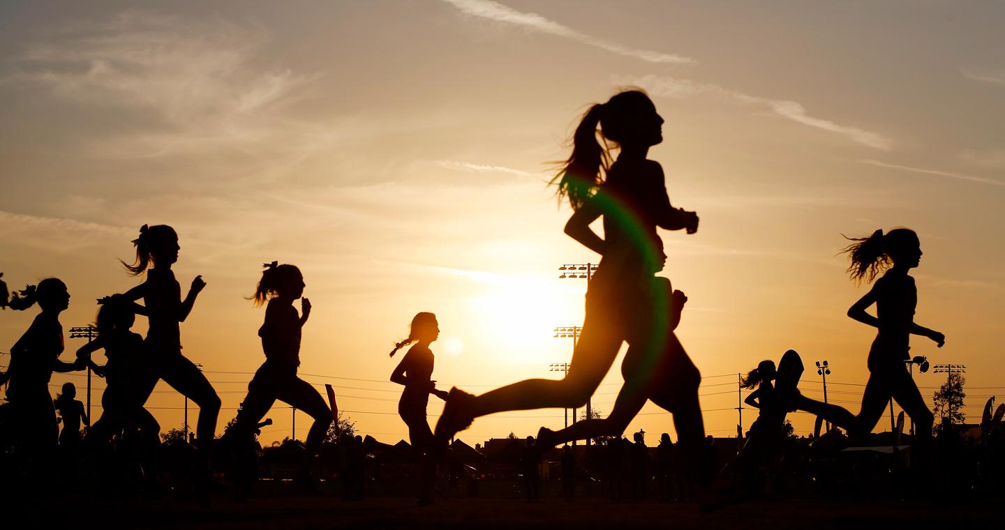 People silhouetted as the run with the sun setting