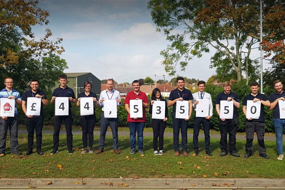 Employees outside holding individual numbers to show fundraising total