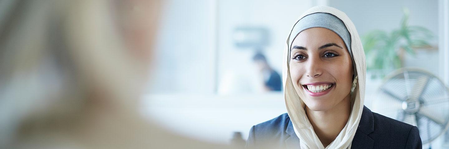 Muslim lady smiling and wearing a head scarf during a meeting