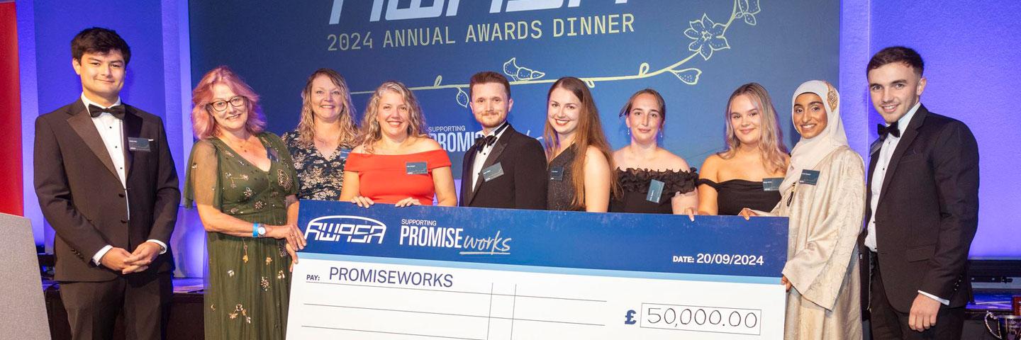 Employees holding a fundraising cheque for PROMISEworks