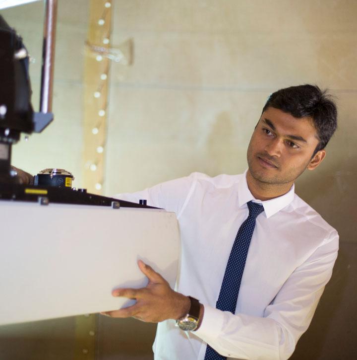 Young Asian man in shirt and tie operates machinery