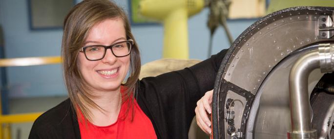 Young woman in glasses smiles and leans on machinery