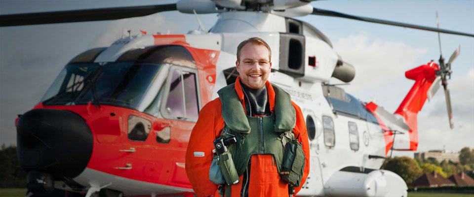 Male Leonardo employee in aircrew attire in front of the Norwegian AW101 Search and Rescue helicopter