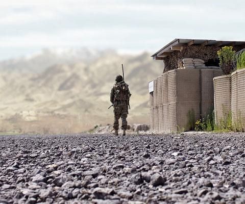 Soldier equipped with Leonardo electronic body armour outside a non-descript military base in barren landscape