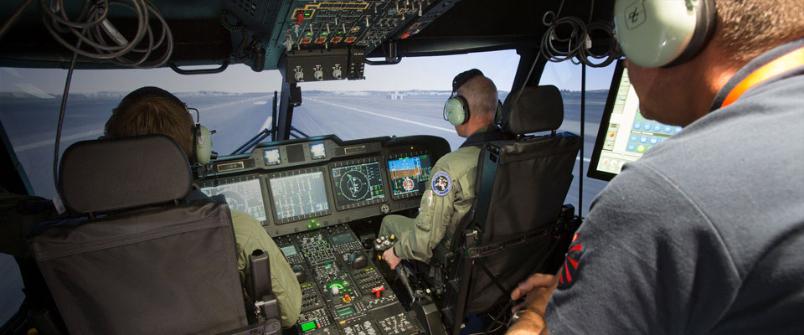 Two aircrew and moderator inside the cockpit of a helicopter full flight simulator
