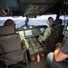 Two aircrew and moderator inside the cockpit of a helicopter full flight simulator